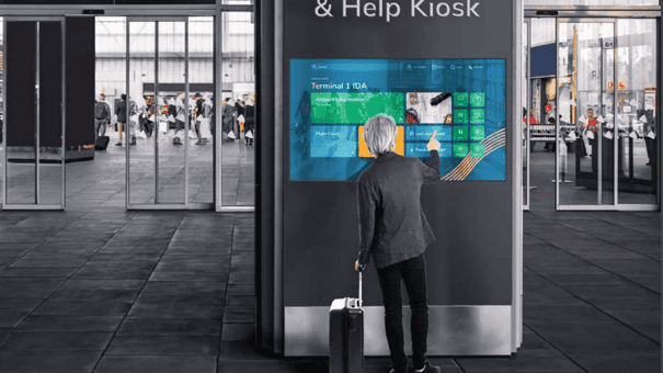 A modern airport with a tourist using a large LV-Tron touch screen display for easy wayfinding